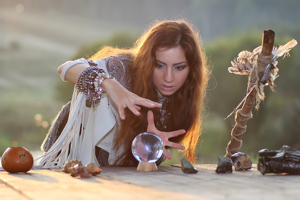 Witch with crystal ball at sunset